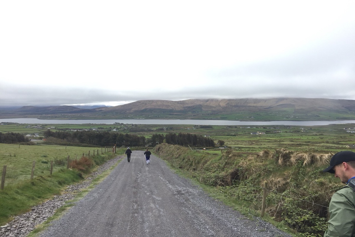 Atlantic puffin flying over the waters of Fjortende Julibukta and a guests kayaking in the water